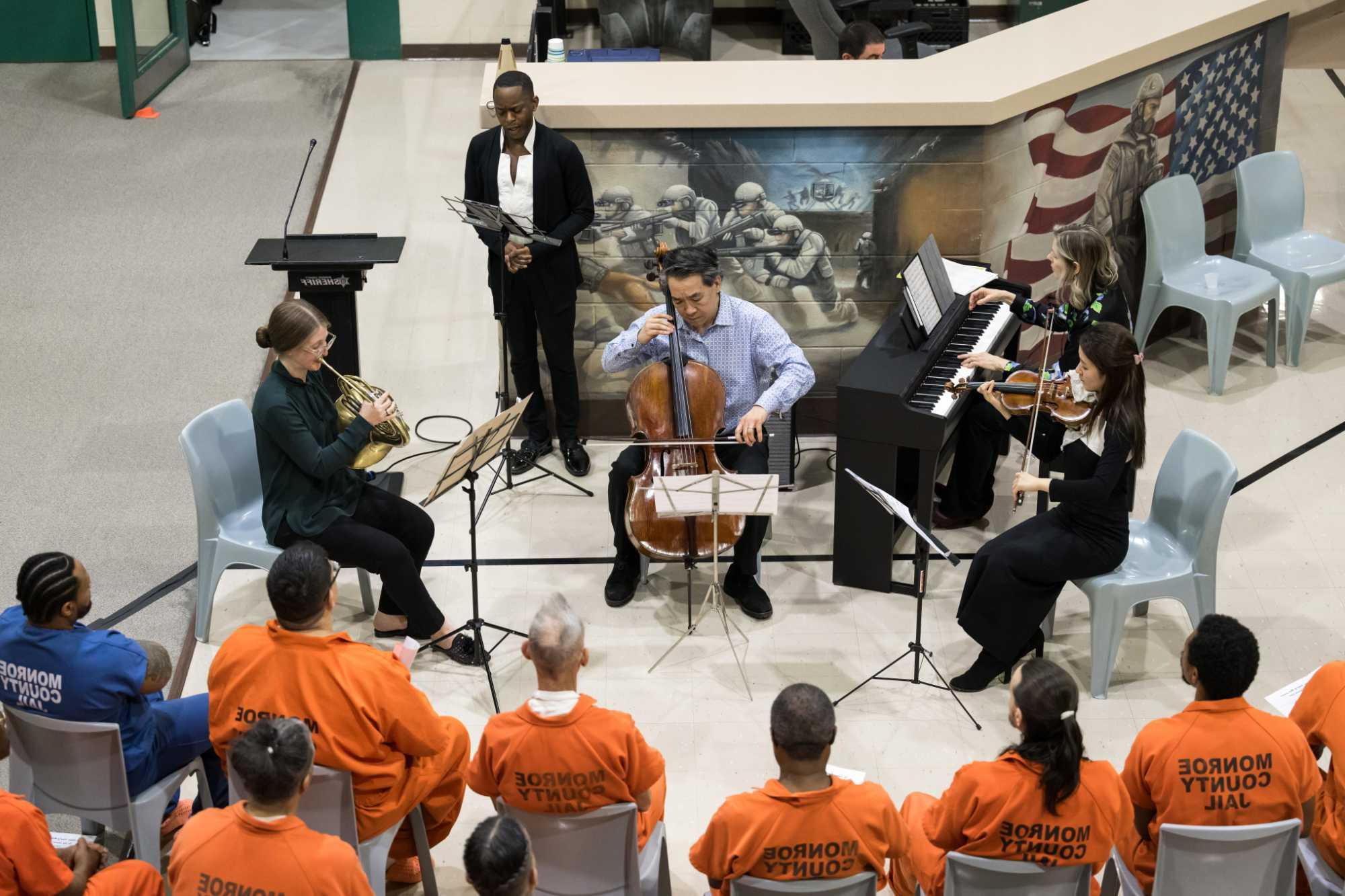 ROC City Concert musicians play their classical music instruments for incarcerated people who are seen from behind.